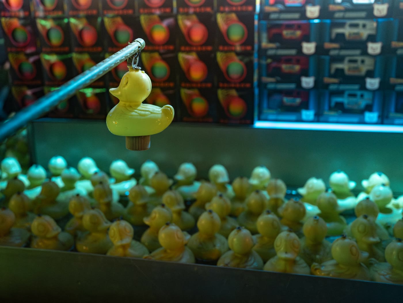 Eine gelbe Ente am Angelhaken über einem Becken mit Spielenten